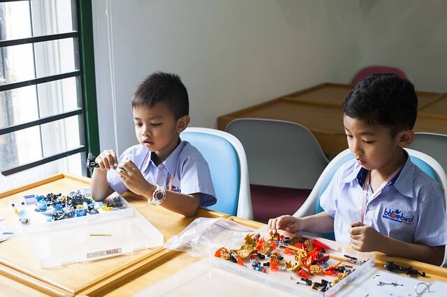 Two school kids playing with construction toys