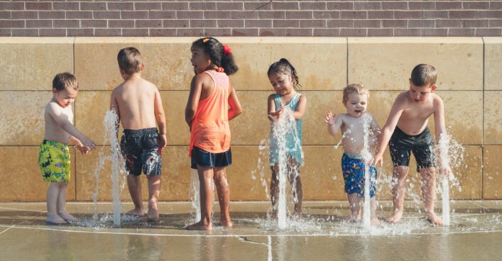 Children of different ages playing with water fountains - age-appropriate activities